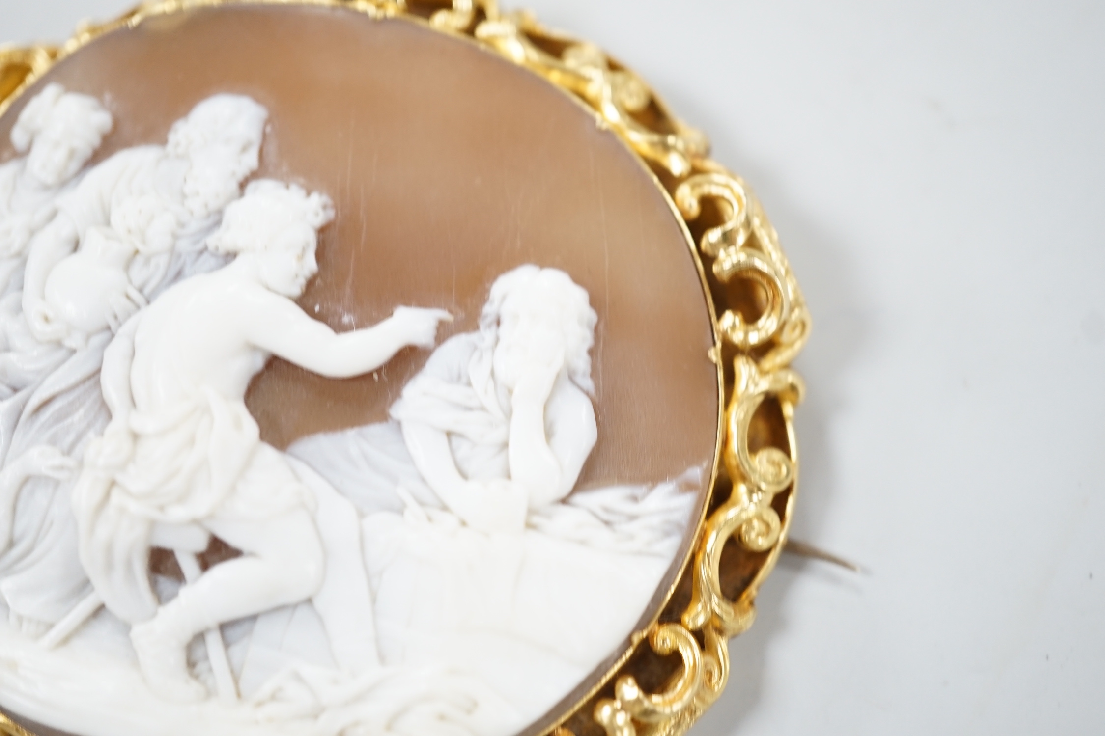 A Victorian yellow metal mounted oval cameo shell brooch, carved with classical figures, width 64mm, gross weight 26.8 grams (pin clasp a.f.).